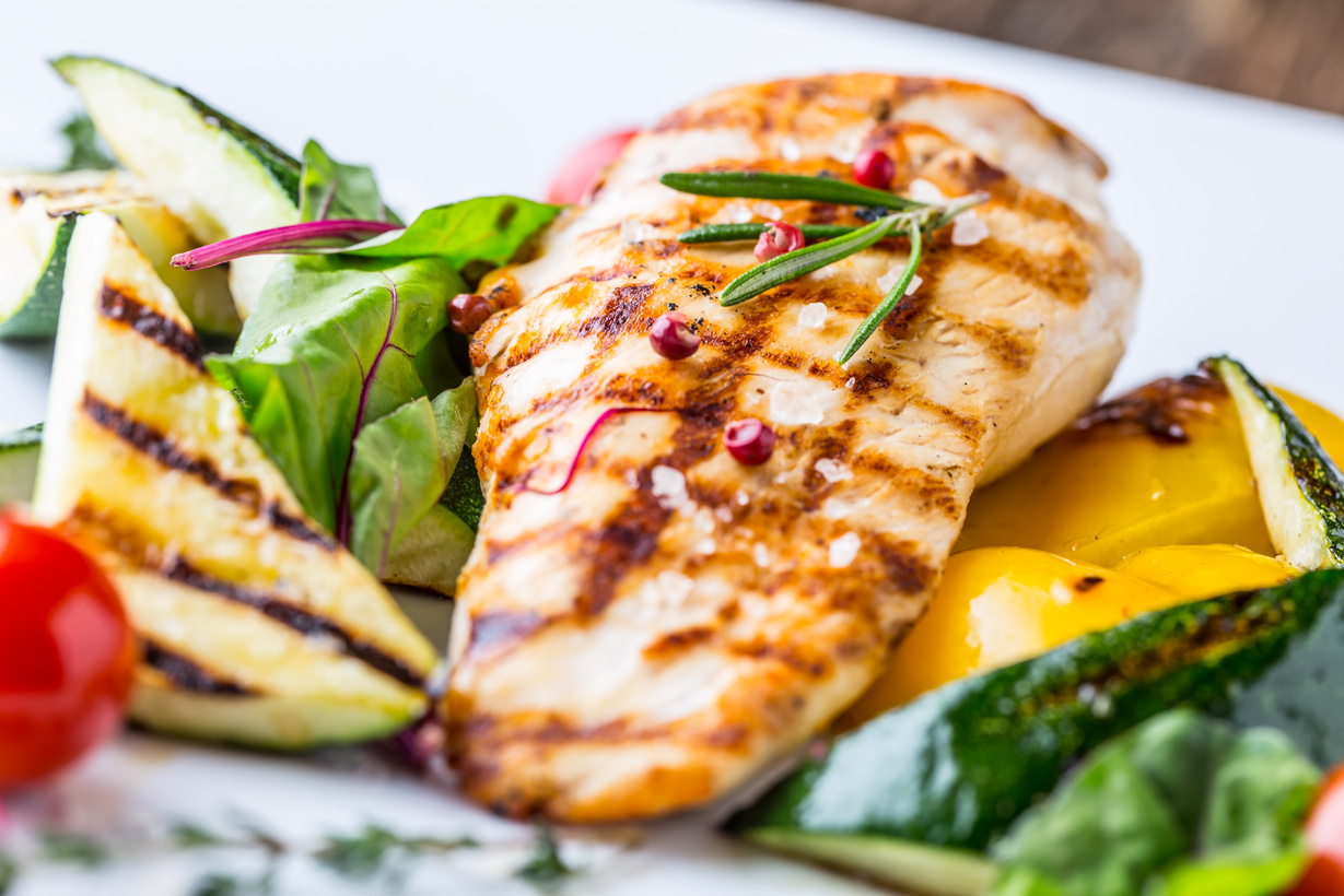 Grill chicken breast. Grilled vegetables with chicken breast. Grilled chicken with vegetables on oak table